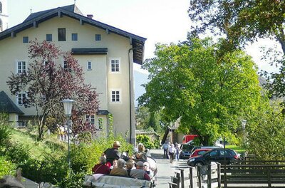 Eine ruhige Straße mit einem großen Gebäude im Hintergrund. Menschen sitzen in einem offenen Fahrzeug und genießen die Landschaft.