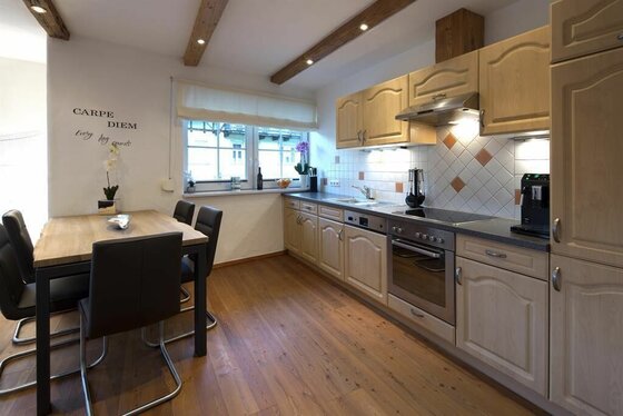 Küche im Appartement Resch Moderne Holzküche mit Esstisch, Einbaugeräten und Deckenbalken.