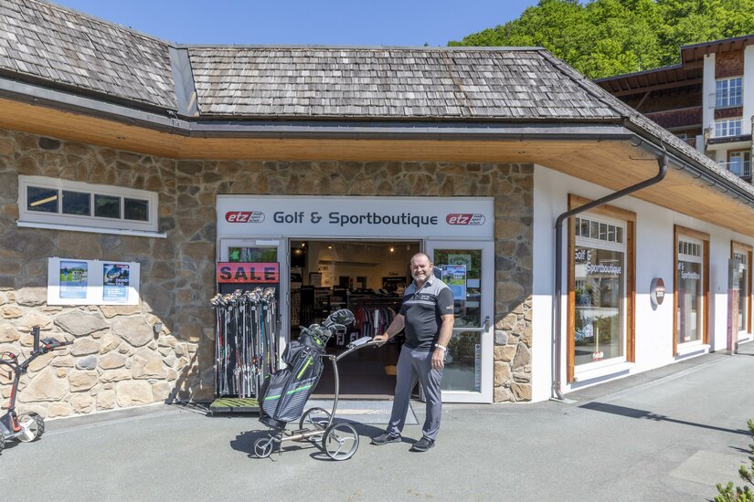 Ein Mann steht mit einem Golf-Trolley vor dem Eingang der ETZ Golf & Sportboutique.