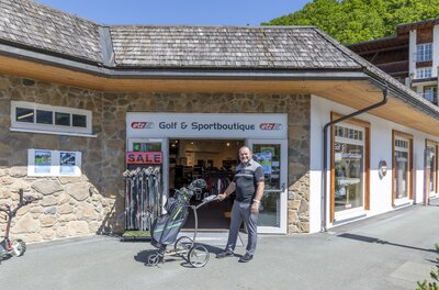 Ein Mann steht mit einem Golf-Trolley vor dem Eingang der ETZ Golf & Sportboutique.