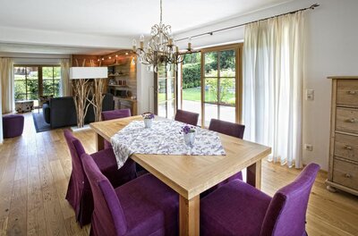 Holztisch mit lila Stühlen in einem hellen Wohn- und Essbereich mit Parkettboden.