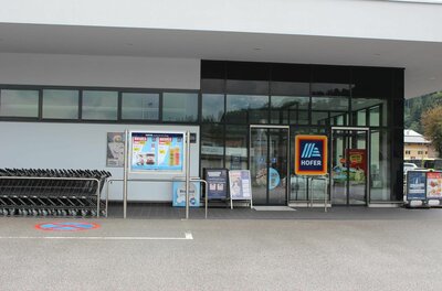 Hofer Supermarkt Eingang Eingangsbereich eines Hofer Supermarktes mit Glasfront, Einkaufswagen und Werbeplakaten.