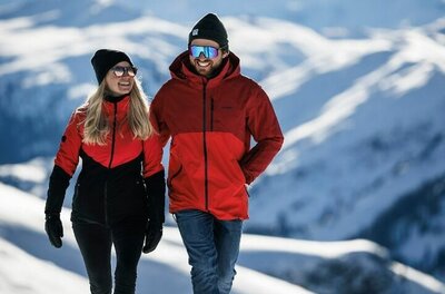 Winterwandern in den Kitzbüheler Alpen Ein Paar in Winterkleidung wandert auf einem verschneiten Bergpfad vor einem alpinen Panorama.