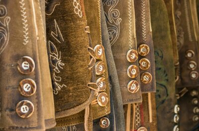 Nahaufnahme von braunen Lederhosen mit hellen Stickereien und Hirschhornknöpfen.