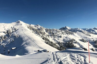 Hochetzkogel Panorama im Winter Verschneite Berglandschaft mit Skispuren im Vordergrund und Blick auf den Hochetzkogel unter blauem Himmel.