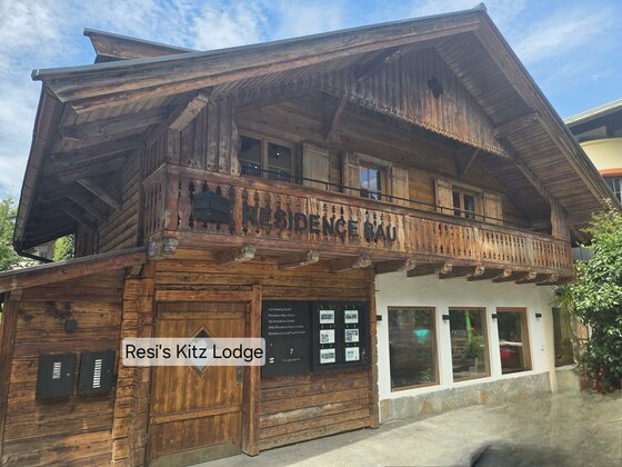 Resi's Kitz Lodge Hausansicht Zweistöckiges Holzhaus im alpinen Stil mit Balkon und Schaukasten an der Fassade.