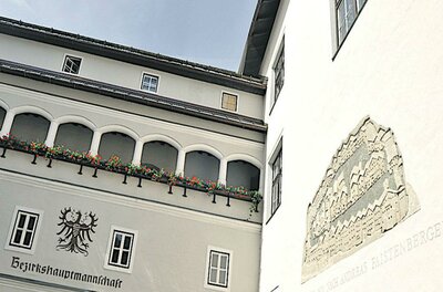 Graffito Ein historisches Gebäude mit kunstvollen Fenstern und Blumenkästen. An der Wand ist ein dekoratives Relief zu sehen.