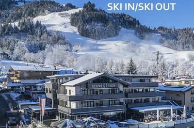 <p>Das moderne Hotel Schweizerhof mit Restaurant in einer verschneiten Berglandschaft. Im Hintergrund ist die Streifabfahrt des Hahnenkamms sichtbar.</p>