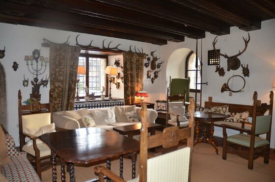 Lounge im Hotel Schloß Münichau Rustikaler Hotel-Aufenthaltsraum mit dunklen Holzbalkendecken, Geweihen an den Wänden und klassischen Sitzmöbeln.