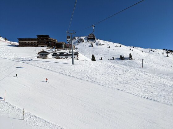 Skipiste mit Gondelbahn Blick auf eine Skipiste mit Gondelbahn und Bergstation vor blauem Himmel.
