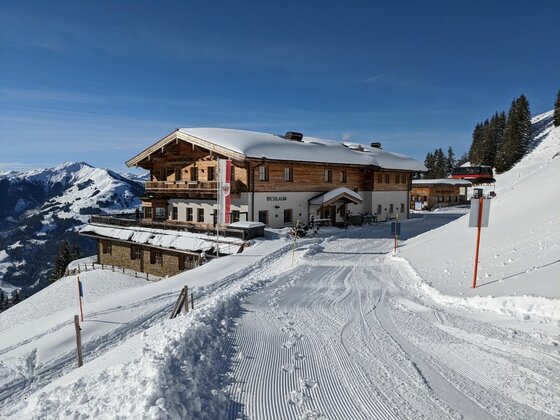Bichlalm im Winter Schneebedeckte Bichlalm in den Alpen mit präpariertem Winterwanderweg im Vordergrund.