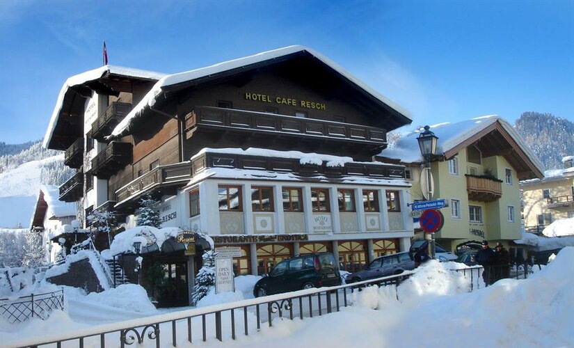 Hotel Resch im Winter Verschneites Hotelgebäude mit Holzfassade und Balkonen unter blauem Himmel.