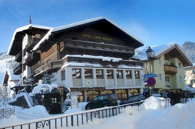 Hotel Resch im Winter Verschneites Hotelgebäude mit Holzfassade und Balkonen unter blauem Himmel.