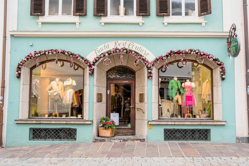 Trachten Eder Ladengeschäft Fassade eines Trachtengeschäfts mit Schaufenstern, die Dirndl und Lederhosen auf Puppen zeigen.