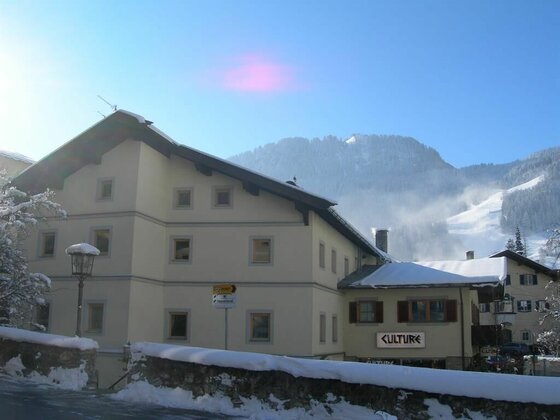 Apartment Gaby im Winter Mehrstöckiges Gebäude mit Schneebedeckung vor bewaldeten Bergen im Winter.