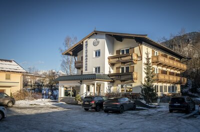 Mehrstöckiges Hotelgebäude mit Holzbalkonen und Parkplatz im Winter.