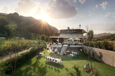 Außenansicht eines Gasthofs mit Gartenrestaurant, Terrasse und angrenzender Wiese vor bewaldeten Bergen.