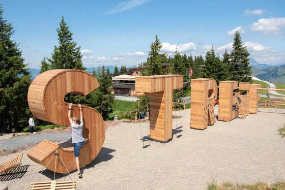 Holz-Kletterelemente am Berg Große Holzbuchstaben als Kletterelemente auf einem Spielplatz in den Bergen.