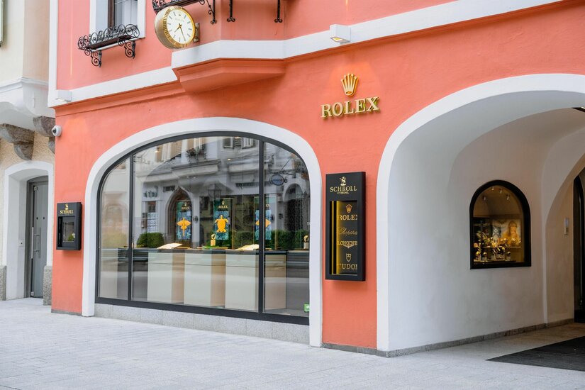 Juwelier Schroll Kitzbühel Außenansicht des Juweliergeschäfts Schroll in Kitzbühel mit lachsfarbener Fassade und Rolex-Logo.