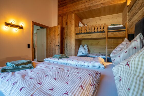 Schlafzimmer Apartment Taxer Schlafzimmer mit Doppelbett und hölzernem Etagenbett in einer alpinen Unterkunft.