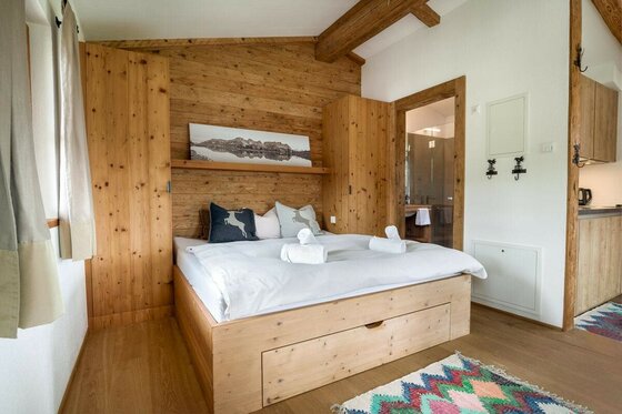 Schlafzimmer im Asten Apartment Schlafzimmer mit Doppelbett aus hellem Holz, Holzwand und Einbauschränken in einem modernen Alpen-Apartment.