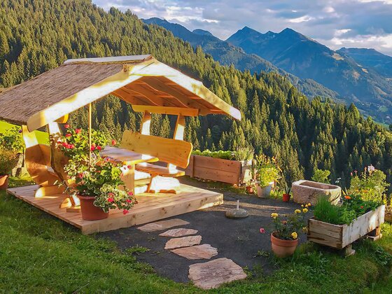 Rastplatz am Bauernhof Hamoos Überdachte Holz-Sitzgruppe im Freien mit Blick auf bewaldete Berge und ein Tal.