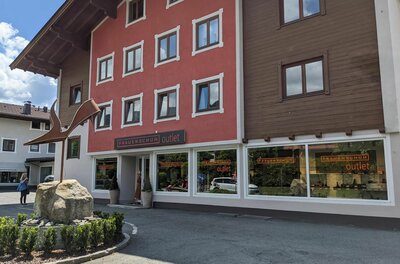 Frauenschuh Outlet Außenansicht des Frauenschuh Outlets in einem mehrstöckigen Gebäude mit roter Fassade und Holzverkleidung.