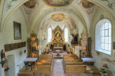Pfarrkirche Aurach Winter Eine schöne Kirche mit einem beeindruckenden Altar und kunstvollen Deckenmalereien. Die Holzbänke bieten Platz für die Besucher.