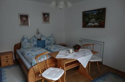 Schlafzimmer mit Doppelbett aus Holz, einem kleinen Esstisch und zwei Stühlen.