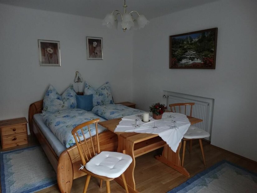 Schlafzimmer im Haus Alpenrose Schlafzimmer mit Doppelbett aus Holz, einem kleinen Esstisch und zwei Stühlen.