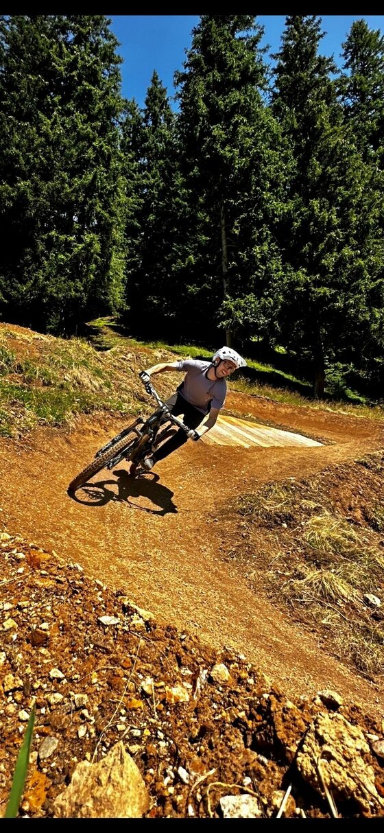 Mountainbiker auf dem Streiteck Trail Ein Mountainbiker fährt durch eine Steilkurve auf einem erdigen Trail im Wald.