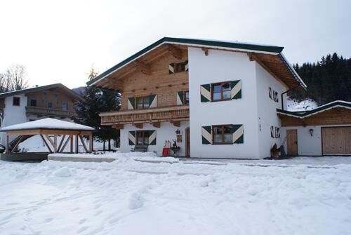 Haus Mitterer im Winter Alpines Wohnhaus mit Holzfassade und weißem Putz in einer verschneiten Landschaft.