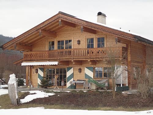 Appartment Ölberg im Winter Zweistöckiges Holzhaus im alpinen Stil mit Balkon und Schneeresten im Vordergrund.