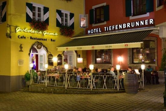 Goldene Gams Terrasse Außenansicht der beleuchteten Terrasse des Restaurants Goldene Gams und Hotels Tiefenbrunner bei Nacht.