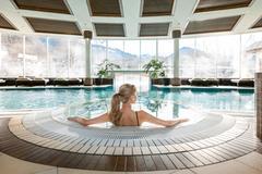 Grand Alp Spa - Grand Tirolia Kitzbühel <p>Der Spa Bereich vom Grand Tirolia Kitzbühel mit einem großen Pool und Blick auf die Kitzbüheler Berge. Eine Frau sitzt am Rand des Pools und genießt die ruhige Atmosphäre.</p>