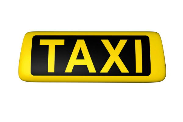 Gelbes Taxi-Schild mit schwarzer Aufschrift auf weißem Hintergrund.