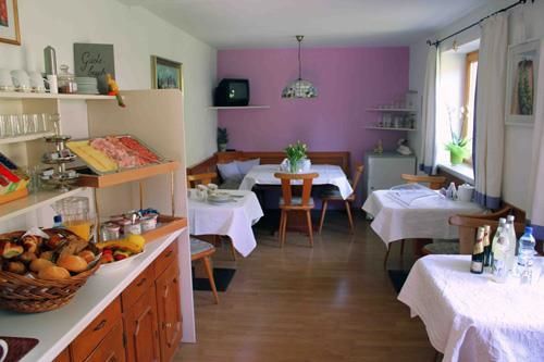 Frühstücksraum Gästehaus Senoner Frühstücksraum mit gedeckten Tischen, Buffetbereich und einer lila Akzentwand.